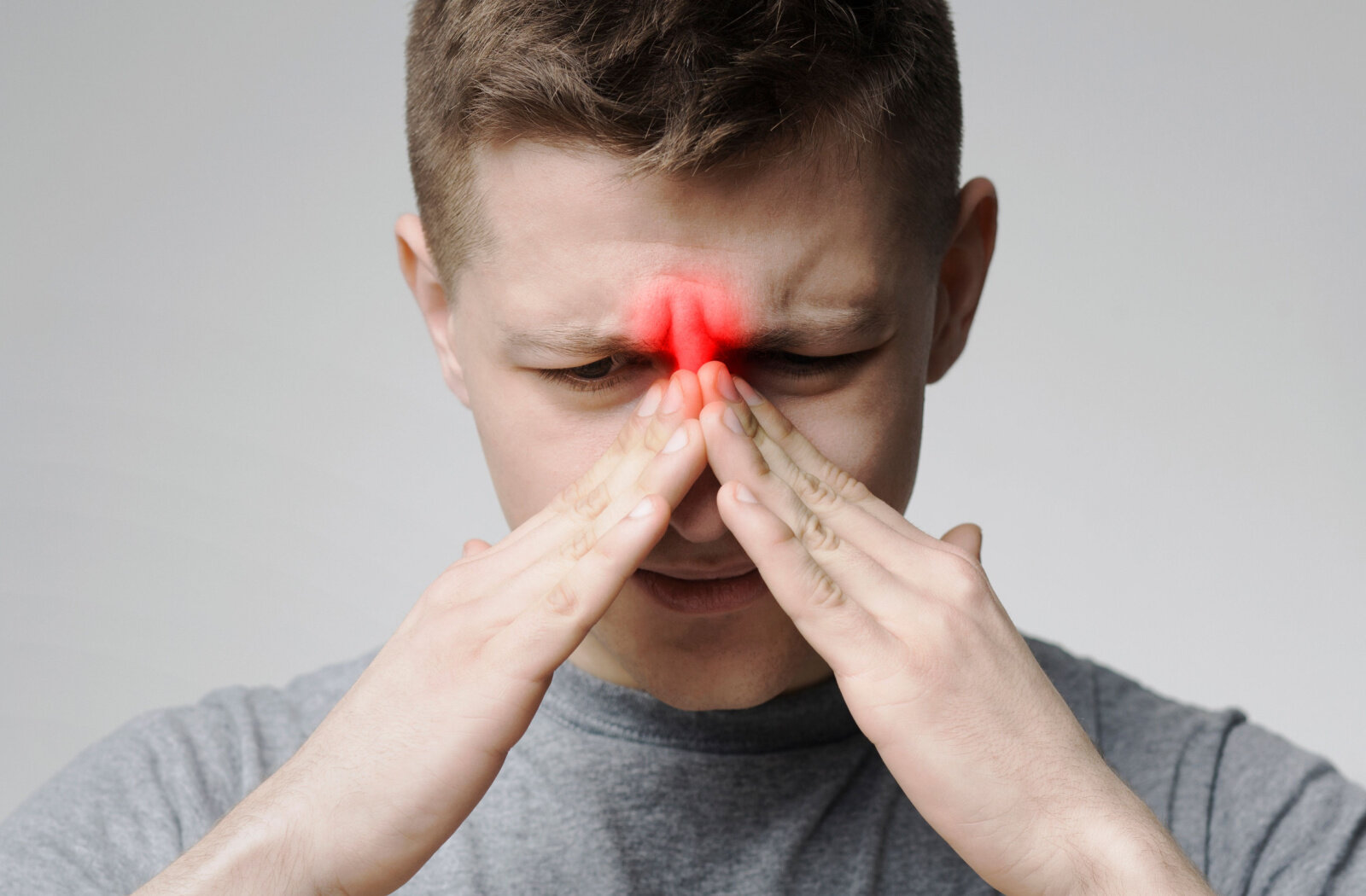 A male is massaging his nose due to sinusitis.