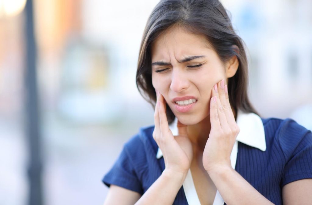 A woman in pain rubs her temporomandibular joints