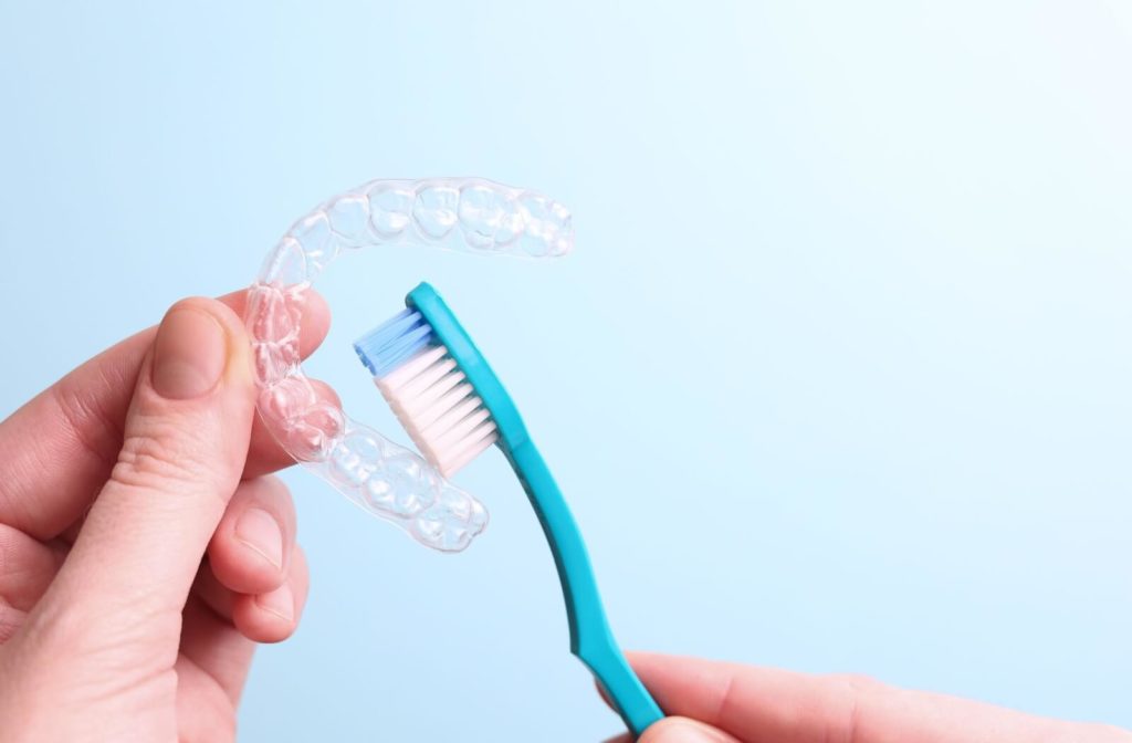 Someone uses a soft brush to clean a clear Invisalign aligner.